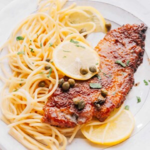 Veal Scallopini on a bed of spaghetti with lemon slices.