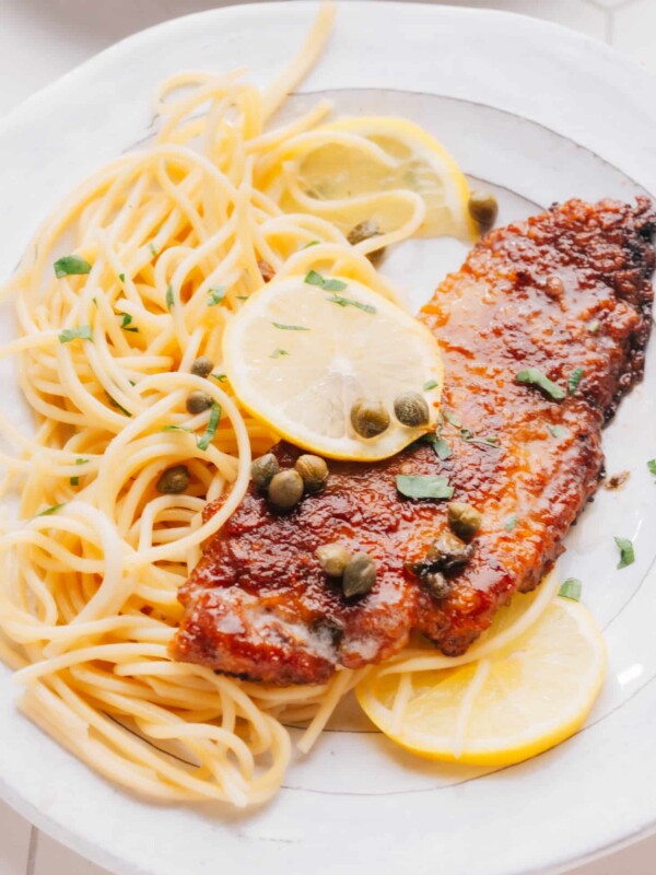 Veal Scallopini on a bed of spaghetti with lemon slices.