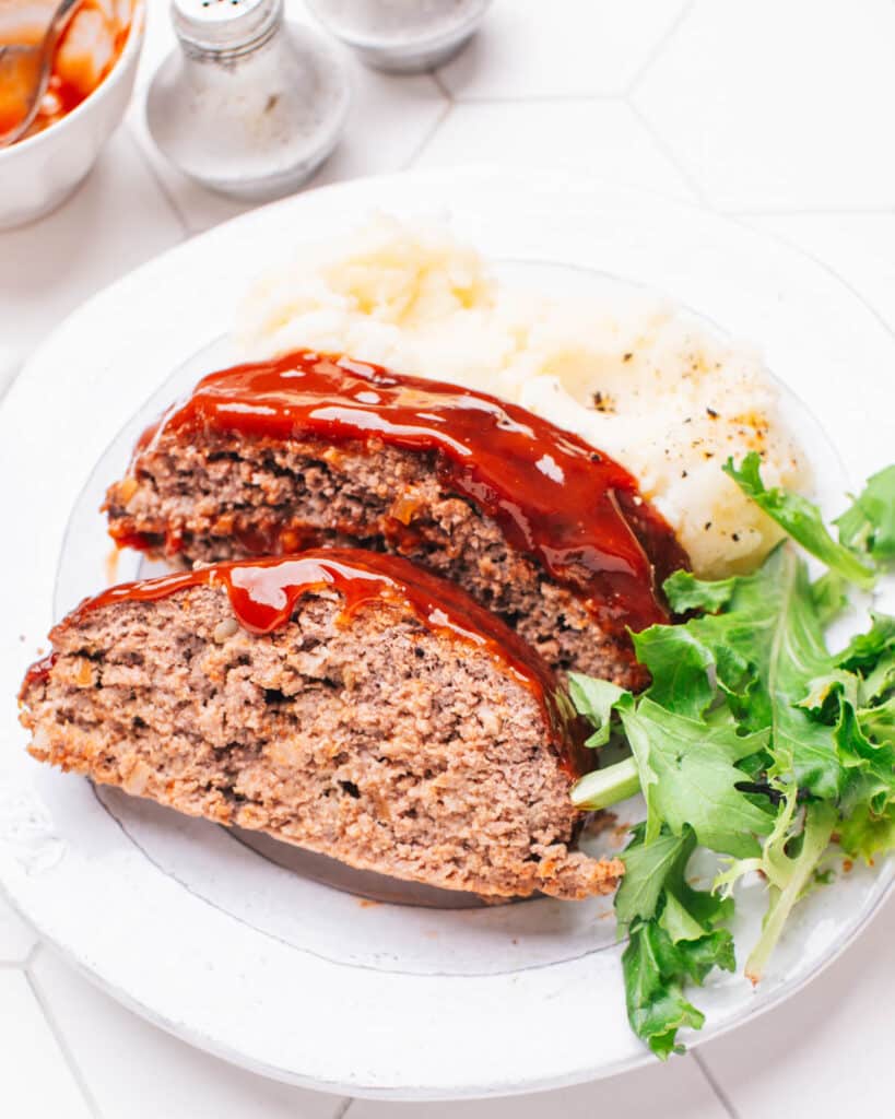 Meatloaf with glaze on a plate with mashed potatoes.