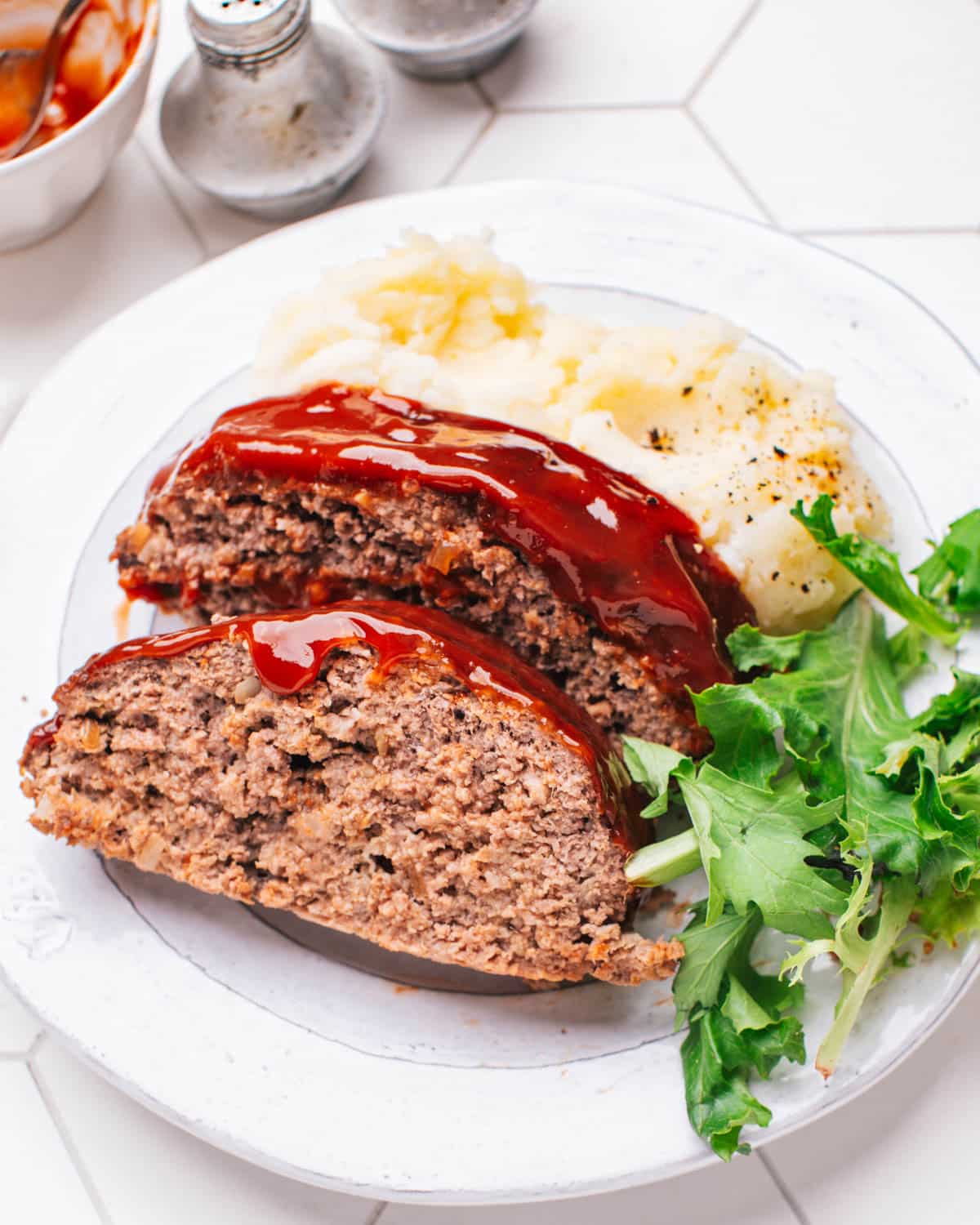 Meatloaf with Glaze on a plate with mashed potatoes.