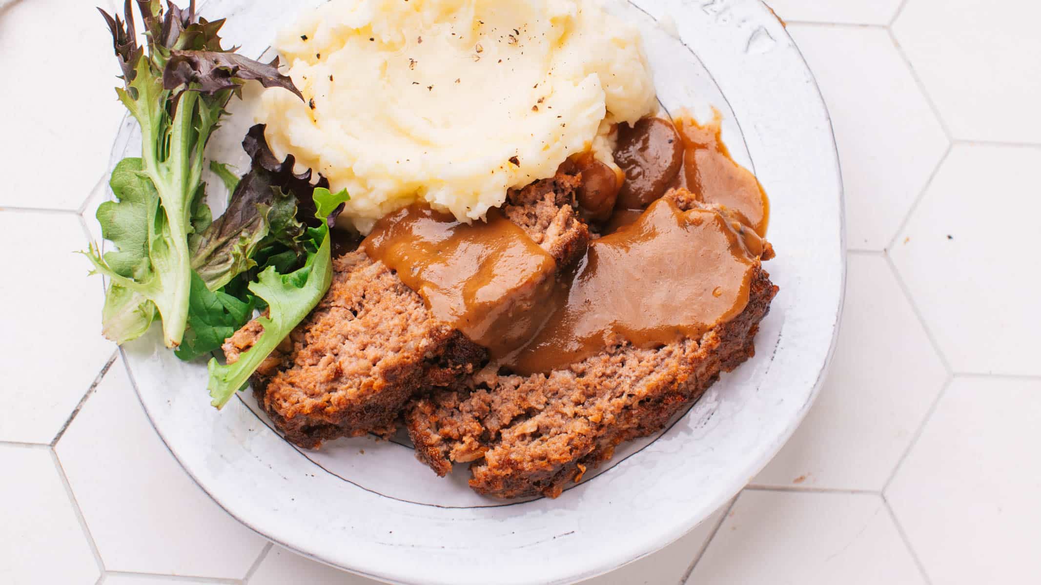 Lipton Meatloaf Recipe and gravy on a plate with side dishes.