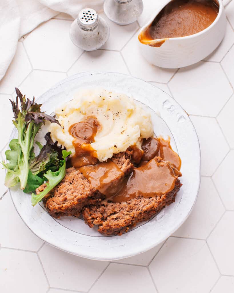Meatloaf with Brown Gravy on a plate with mashed potatoes.