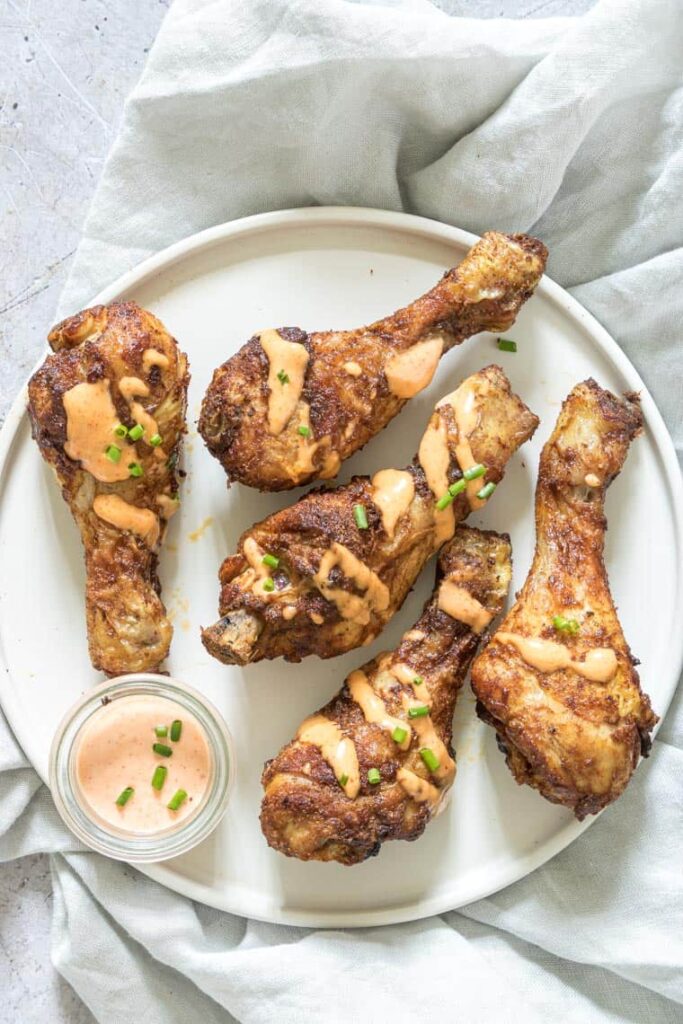 Air Fryer Chicken Drumsticks on a white plate with dipping sauce