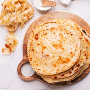 Paratha on a board with some showing their flaky layers