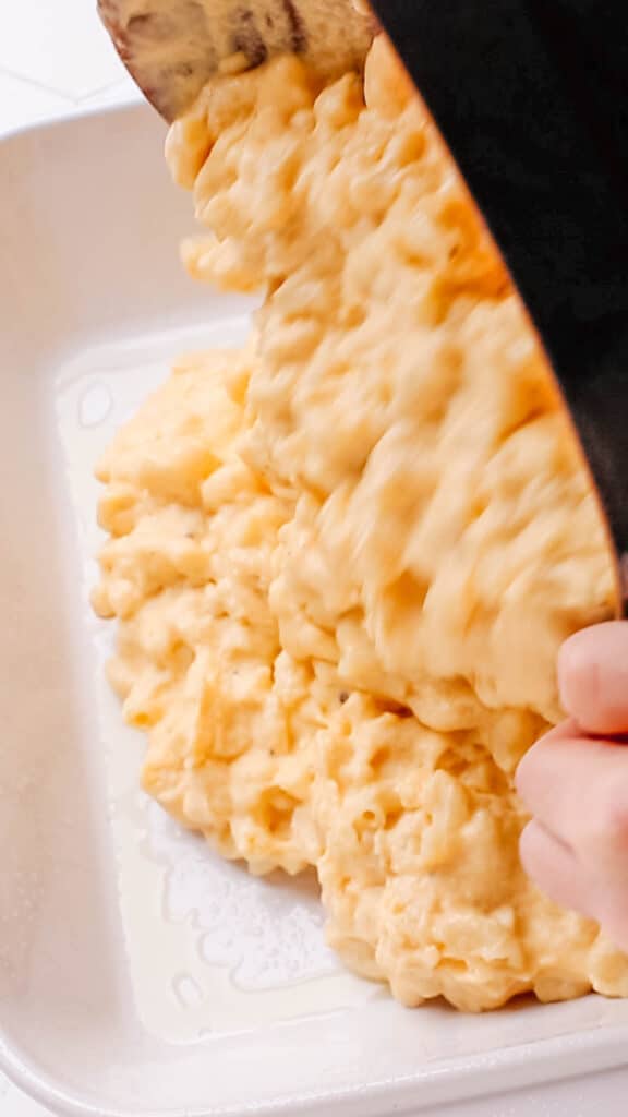 Transferring macaroni and cheese to casserole.