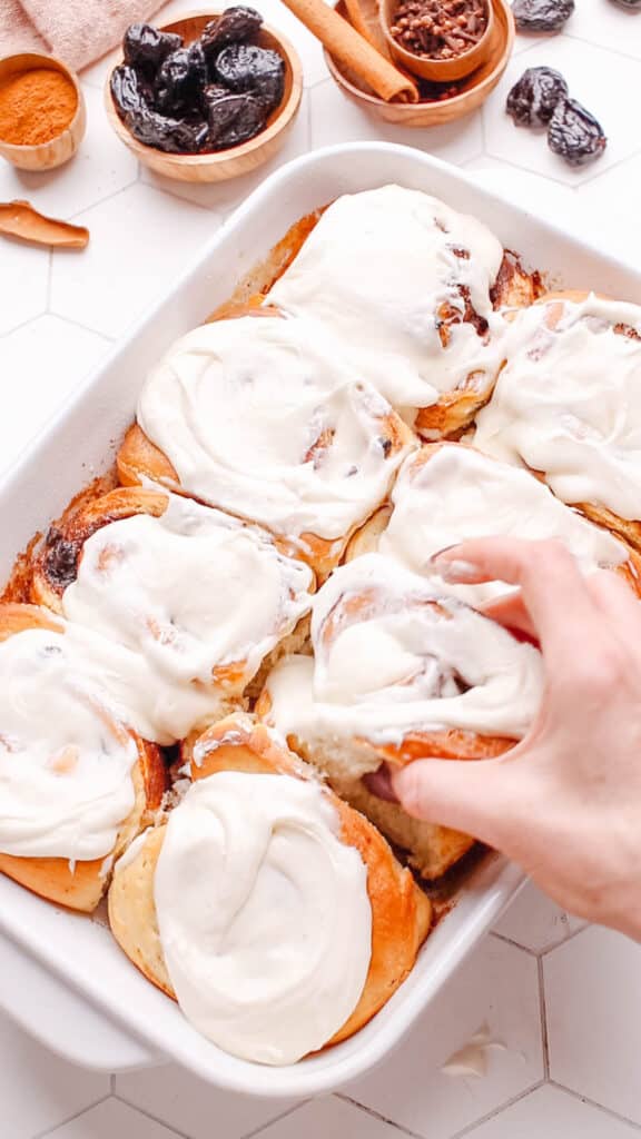 Pulling out a cinnamon raisin roll with cream cheese frosting. 