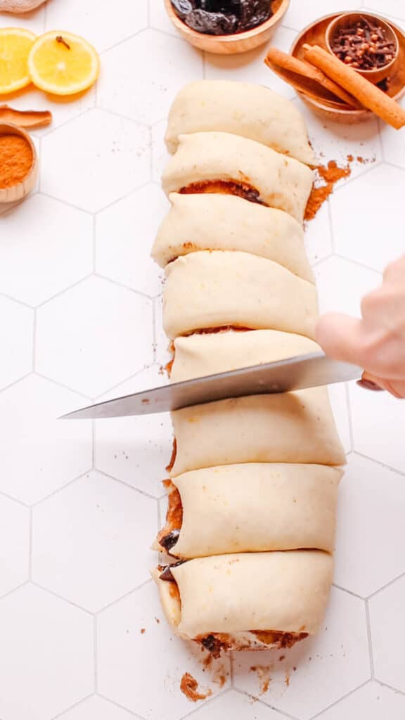 Slicing the cinnamon roll dough into slices.