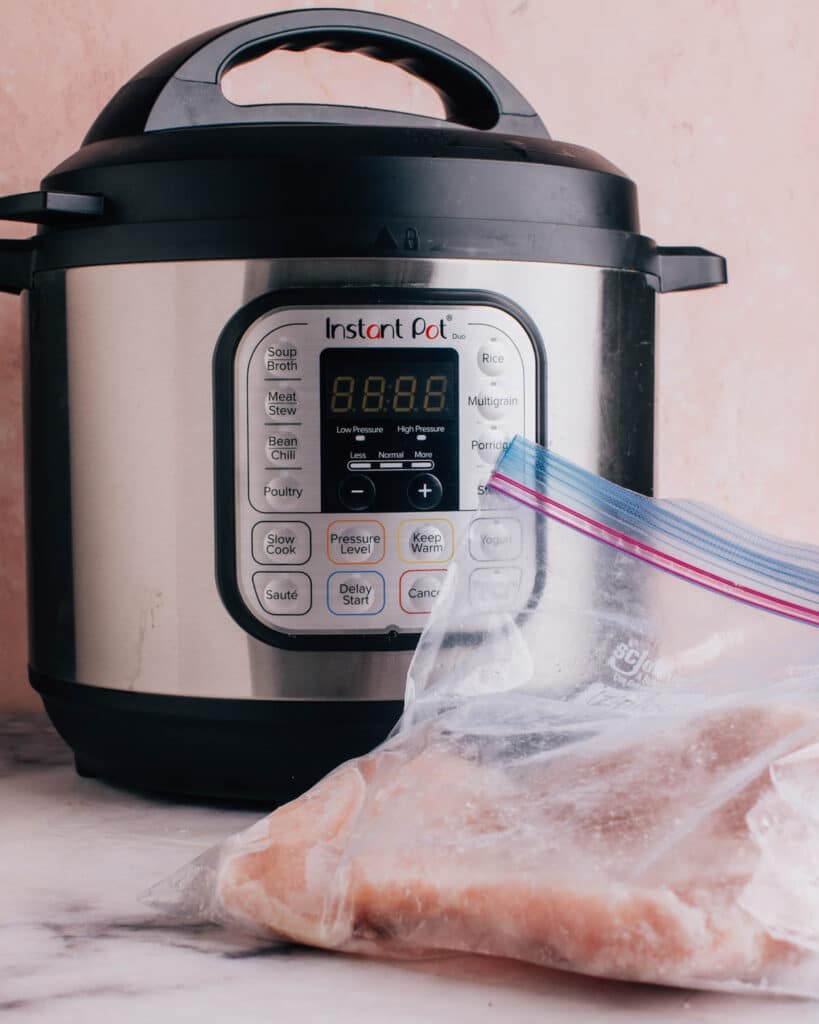 Instant pot with bag of chicken in front.