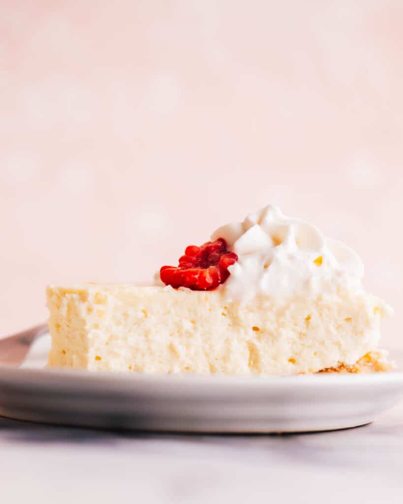 Philadelphia cheesecake with whipped cream and raspberry.