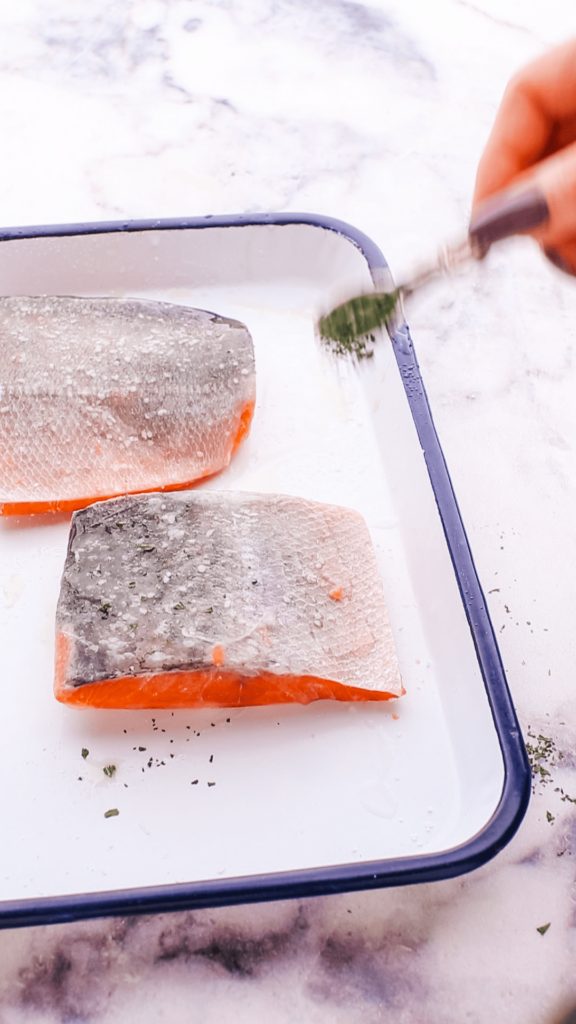 Sprinkling salt and other ingredents on salmon.