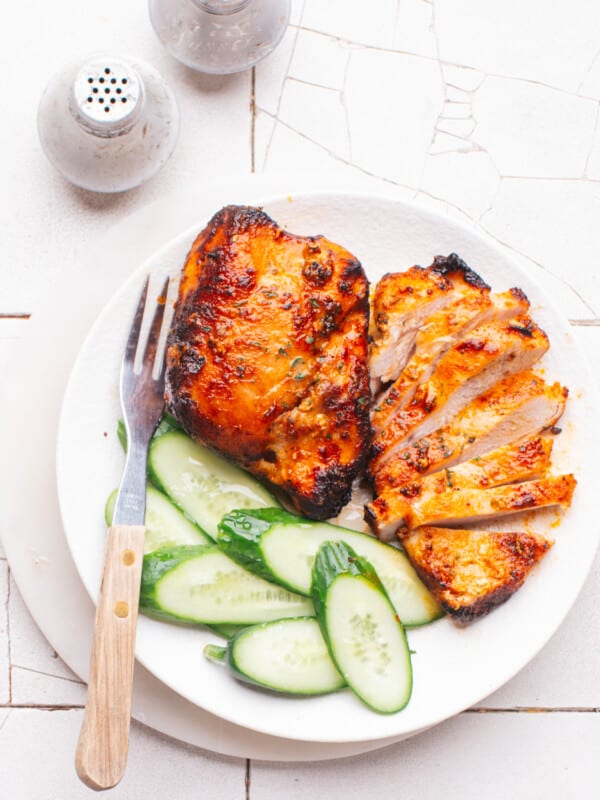 Air Fryer Frozen Chicken Breast sliced on a plate with cucumbers.