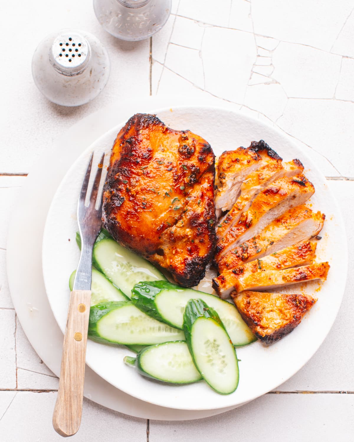Air Fryer Frozen Chicken Breast sliced on a plate with cucumbers.