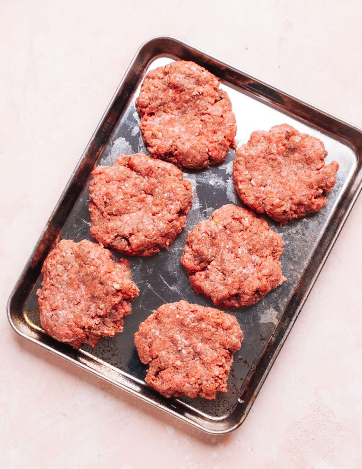 Raw ground beef patties on a tray.