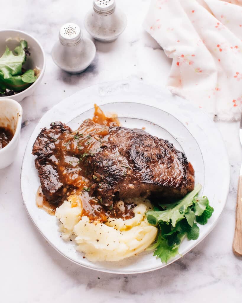 Instant pot steak on a plate with mashed potatoes.