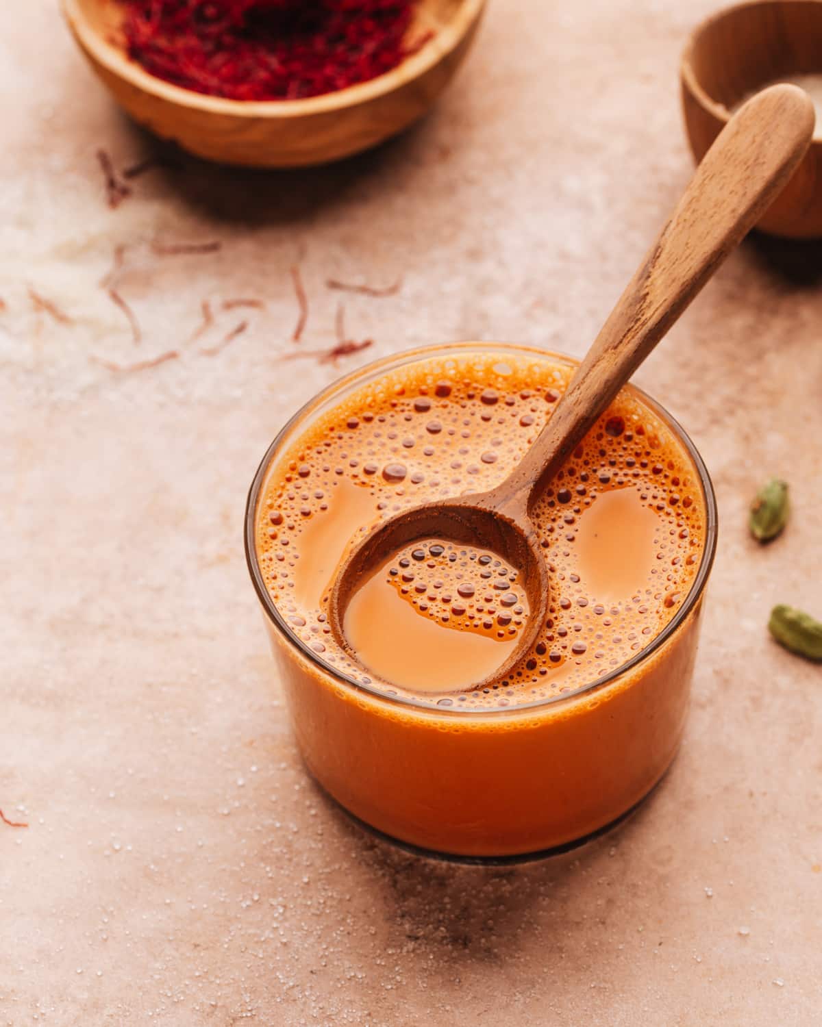 Karak chai in a glass with a spoon. 
