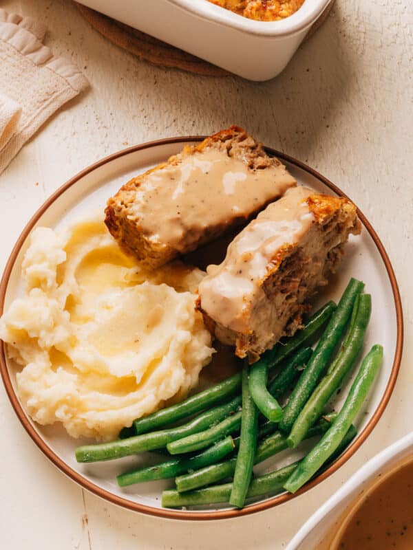 Moist Turkey Meatloaf recipe on a plate with mashed potatoes and green beans.