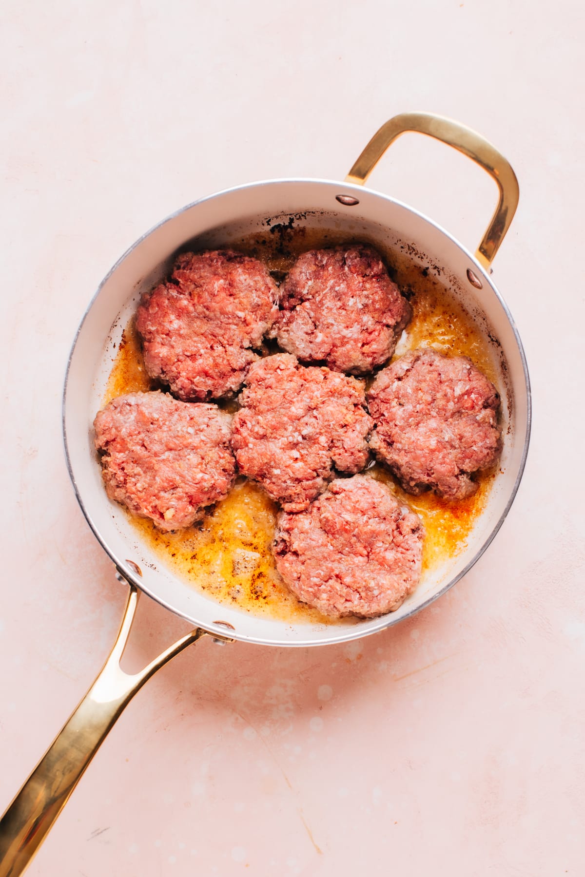 Raw hamburger steak patties in a pan before cooking. 