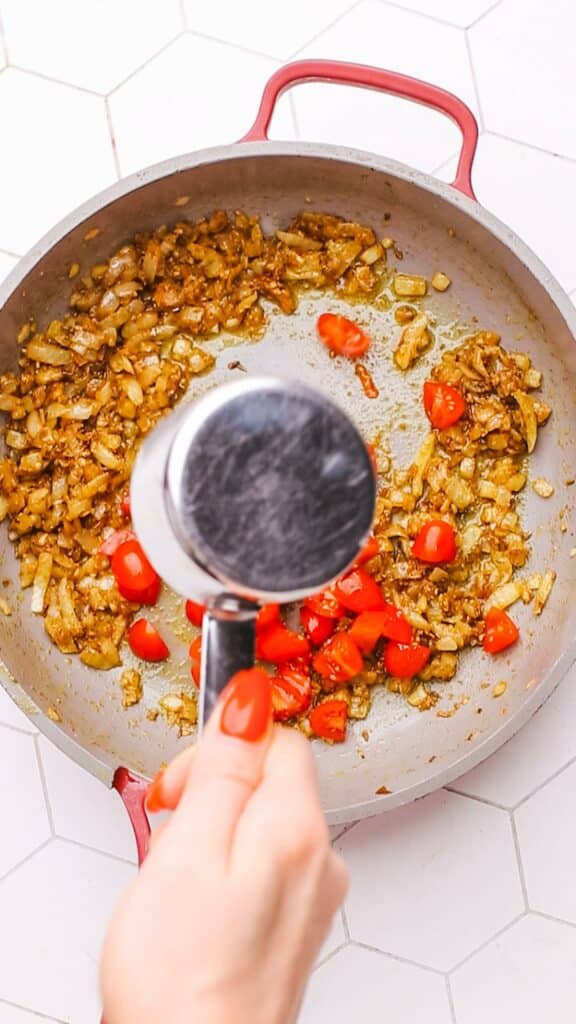Adding tomatoes to palak paneer sauce.