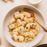 Bowl of homemade potato gnocchi in butter sauce with parmesan and fresh parsley.