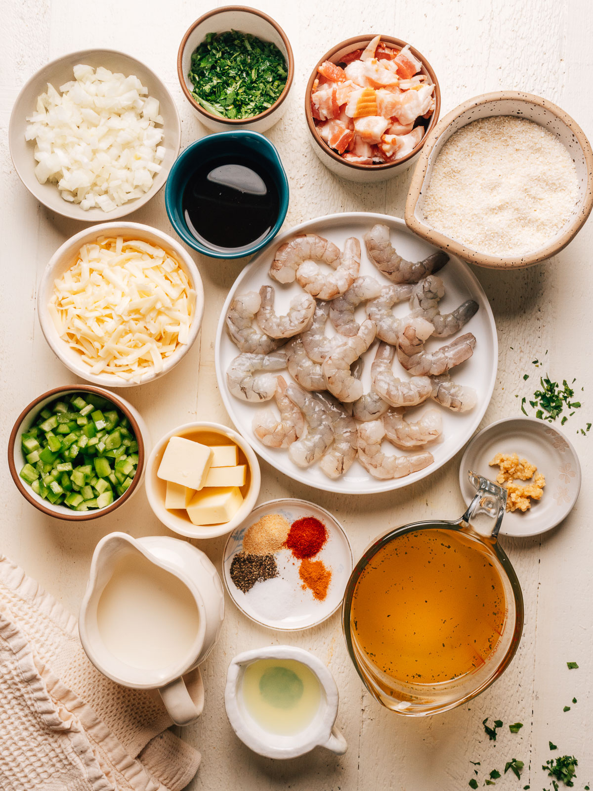 Ingredients for shrimp and grits laid out in bowls, including raw shrimp, grits, cheddar, bacon, onion, and bell pepper.