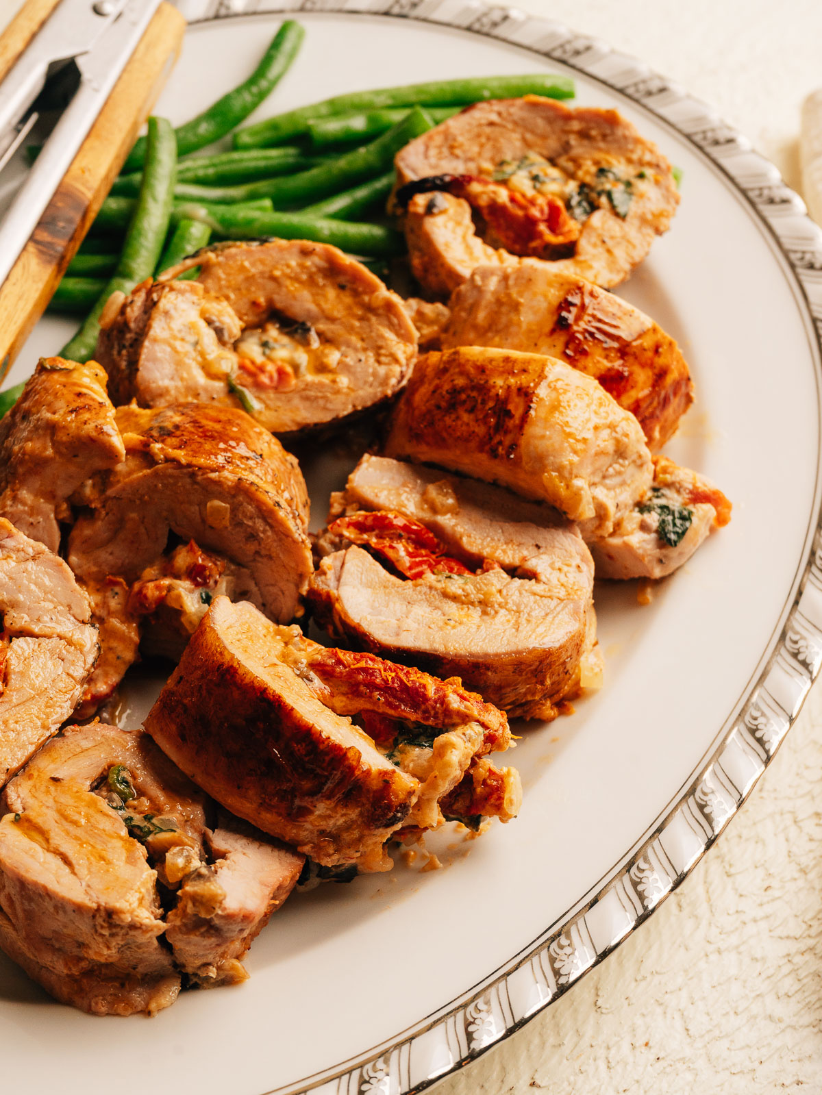 Sliced stuffed pork tenderloin showing creamy sun-dried tomato and spinach filling.