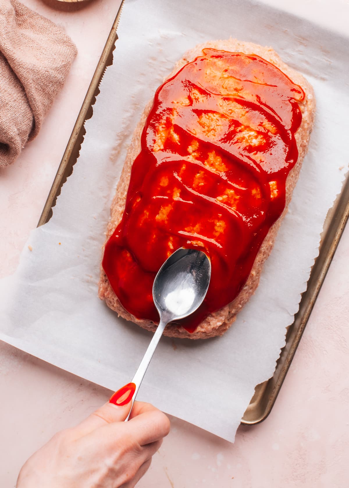 Spreading sauce on meatloaf with spoon