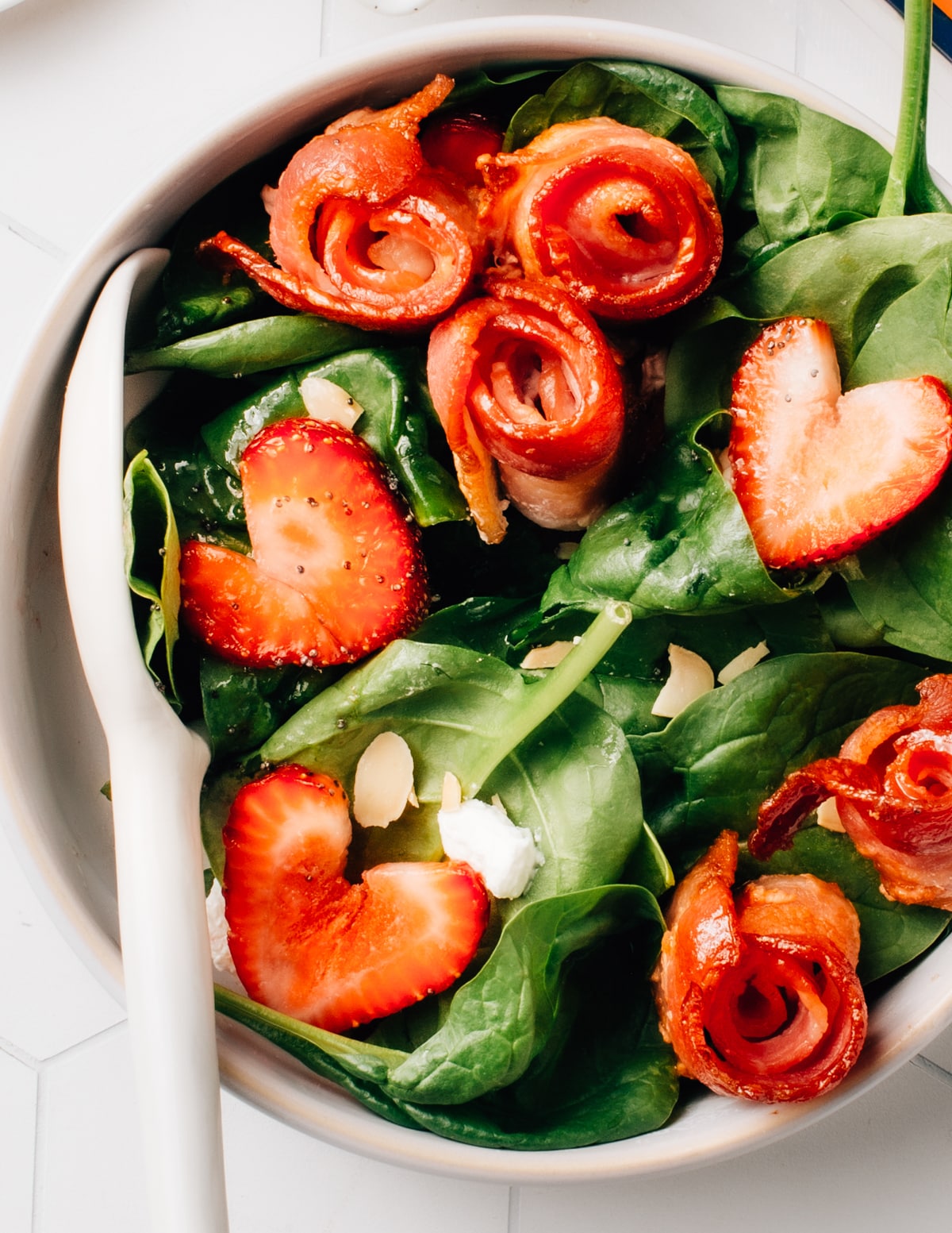 Spinach salad topped with strawberries and air fryer bacon.