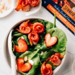 Crispy air fryer bacon on top of a spinach salad with strawberries.