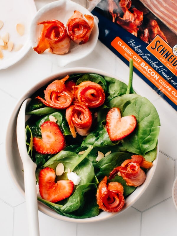 Crispy air fryer bacon on top of a spinach salad with strawberries.
