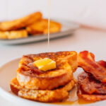 Best french toast on a plate with bacon.