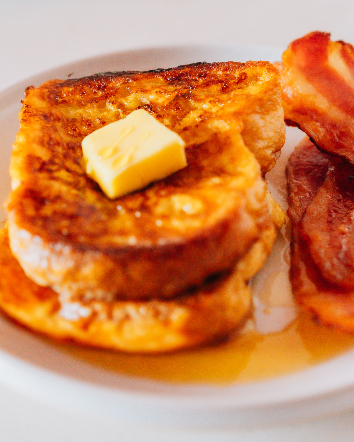 Best french toast on a plate with bacon.