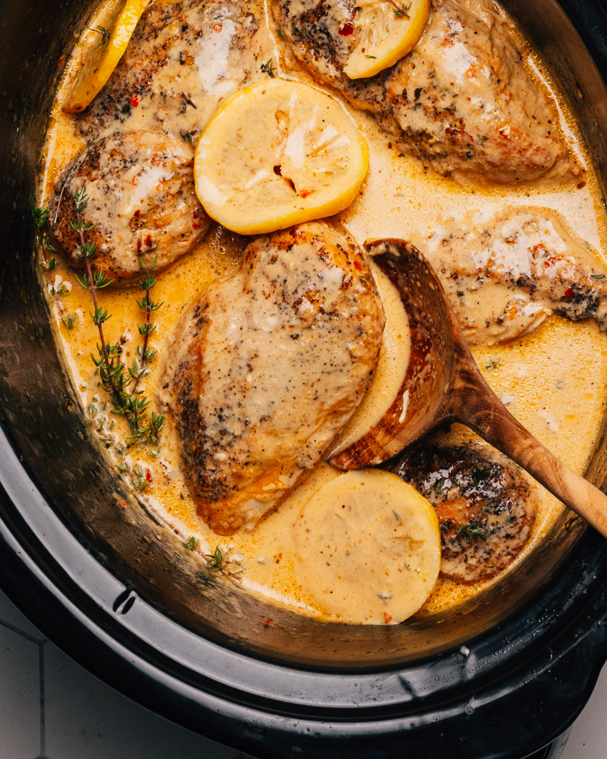 Crockpot Lemon Chicken with a wooden spoon.