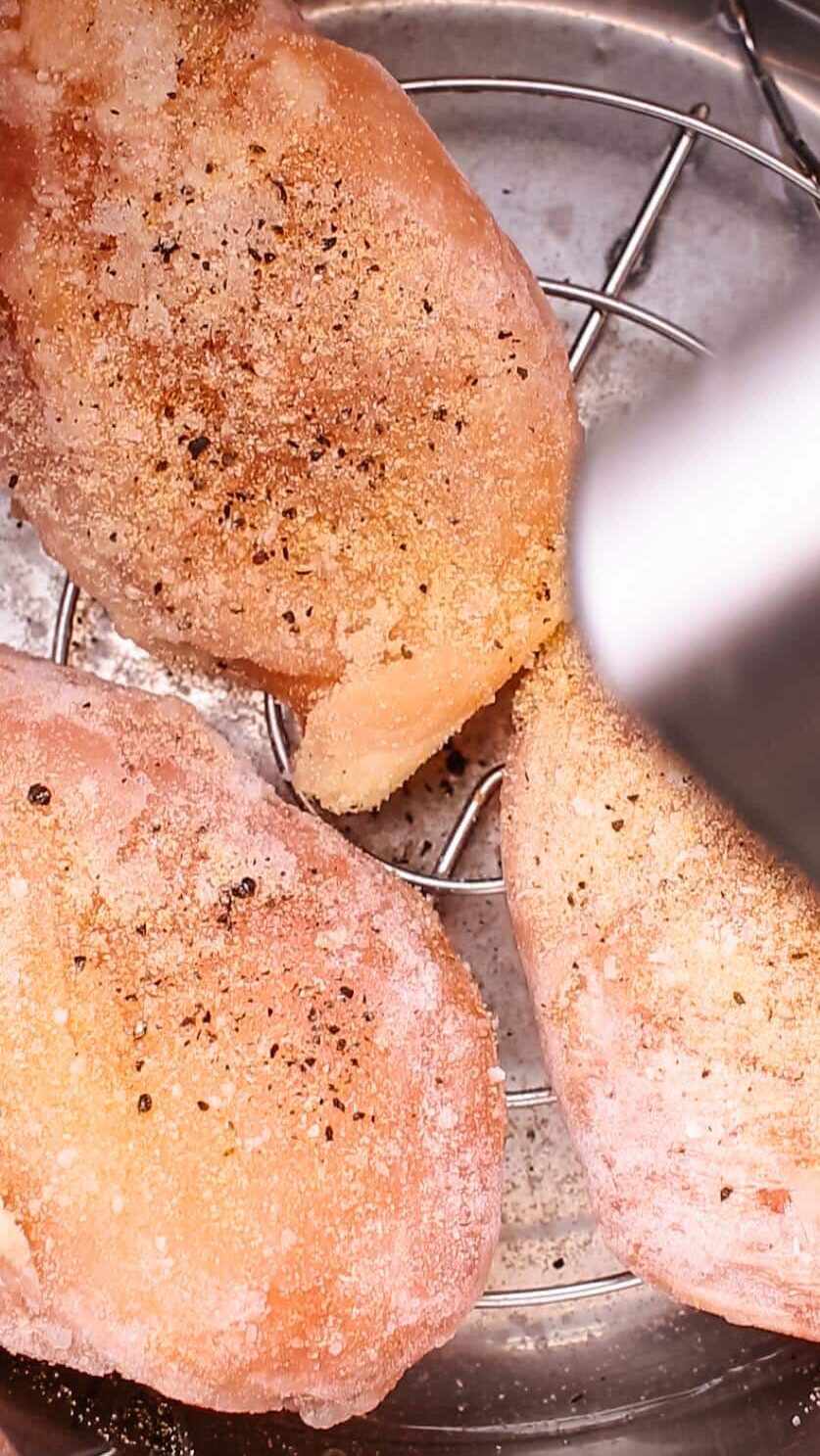 Instant pot frozen chicken breasts with pepper being added.
