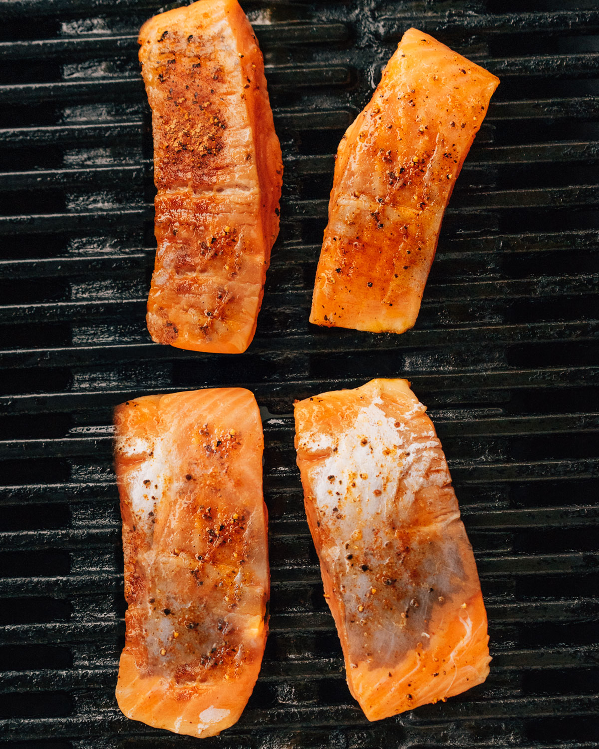 Pieces of salmon on grill grates.