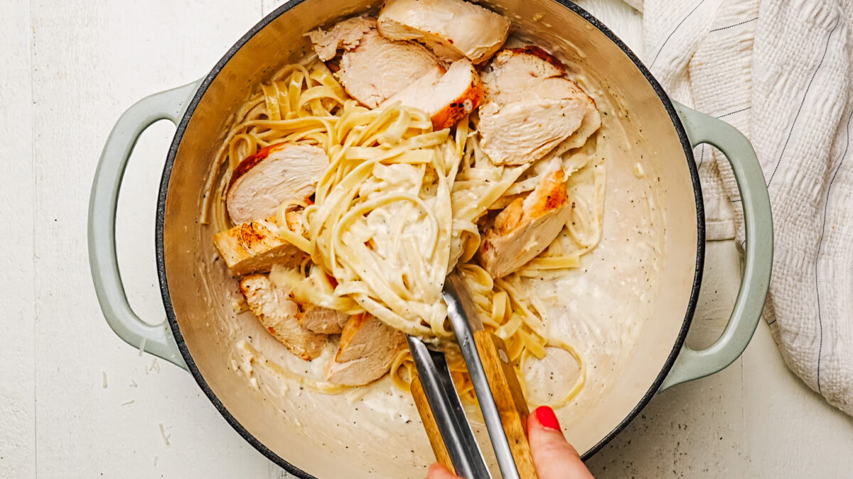 Tossing fettuccine in creamy Alfredo Sauce with sliced chicken.
