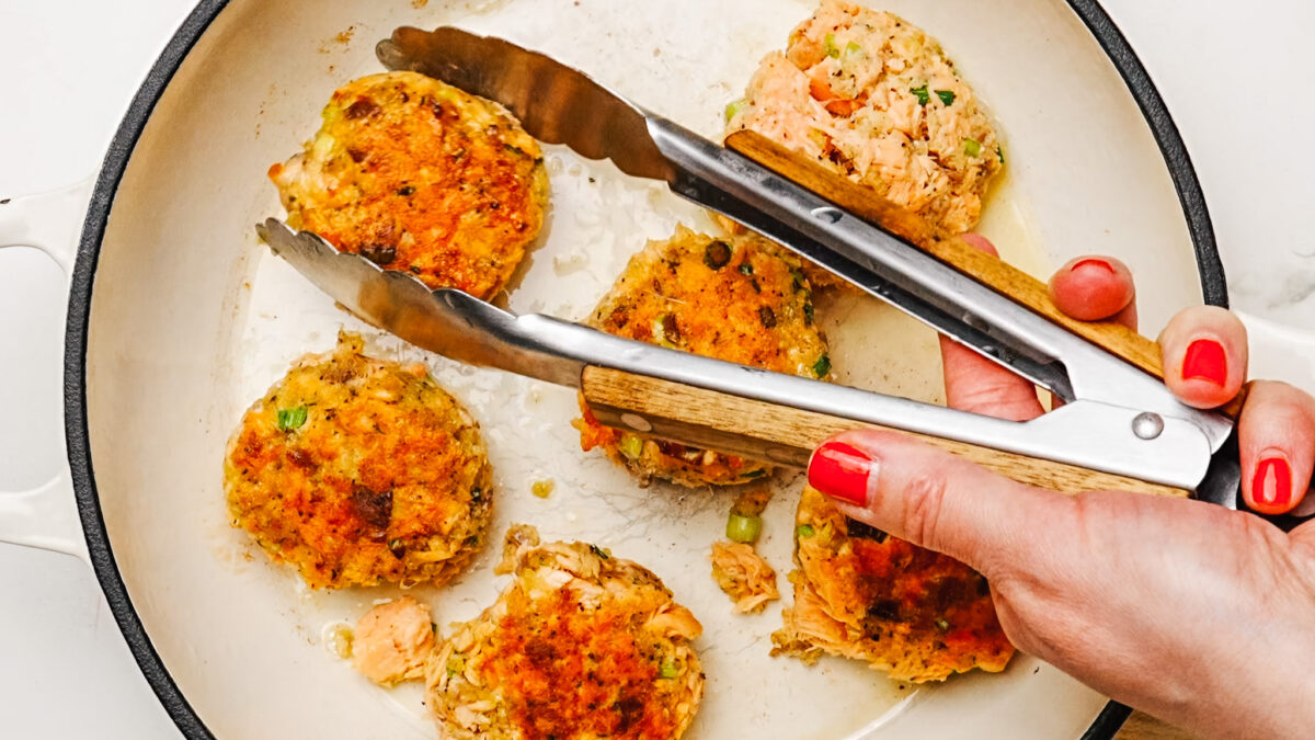 Frying six salmon patties in a skillet with oil.