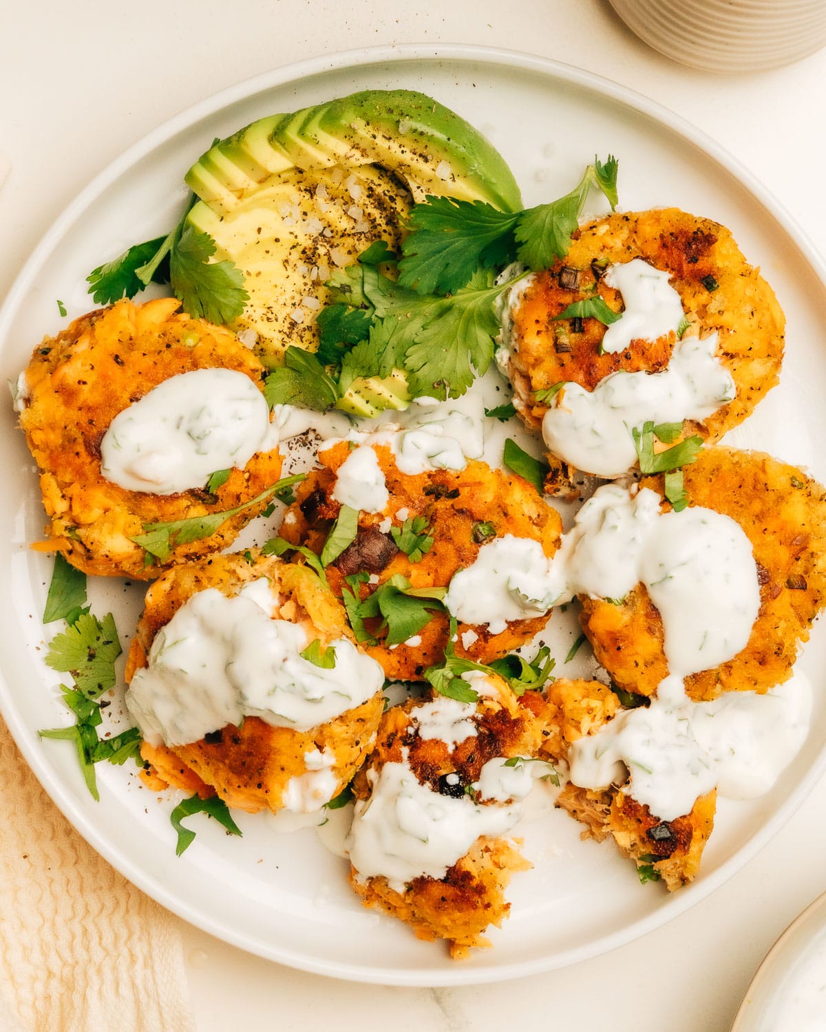 Cooked salmon patties topped with dill sauce, ready to be served.