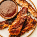 Spare ribs on a plate with barbecue sauce.