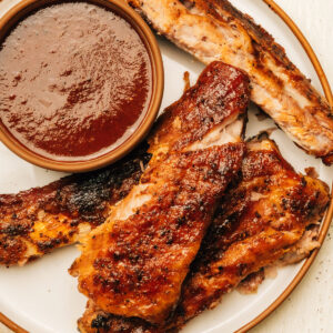 Spare ribs on a plate with barbecue sauce.