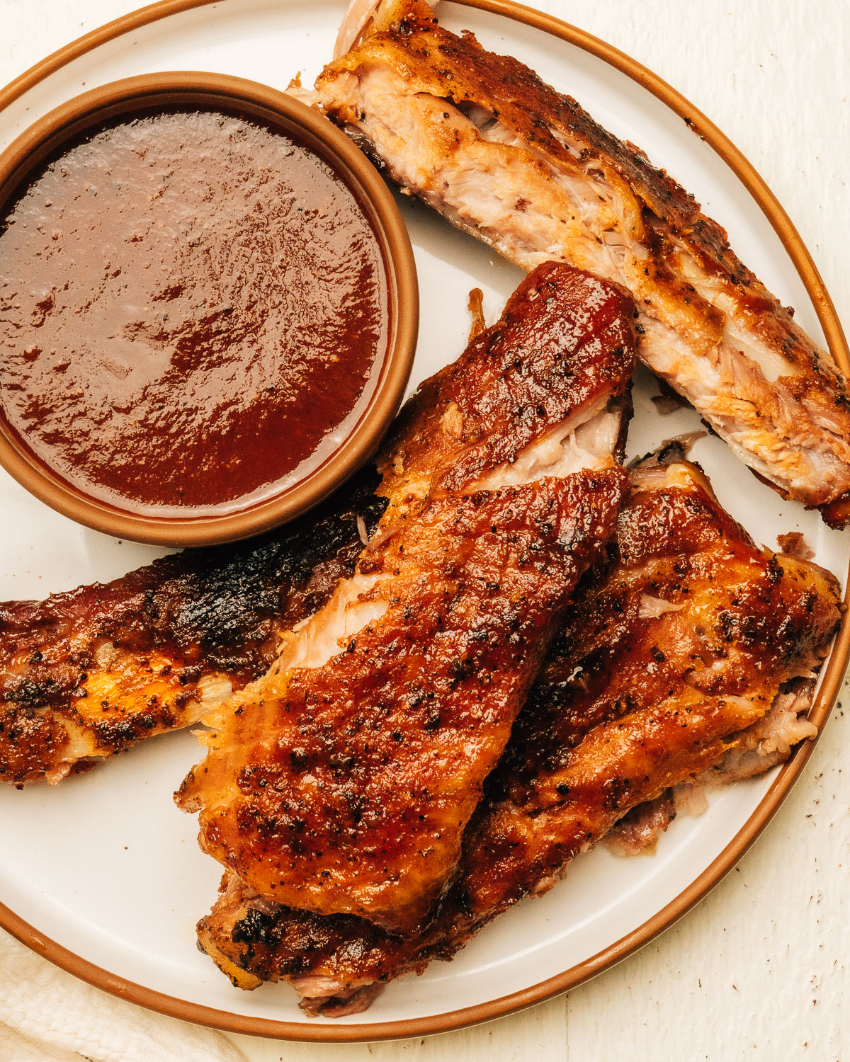 Spare ribs on a plate with barbecue sauce.