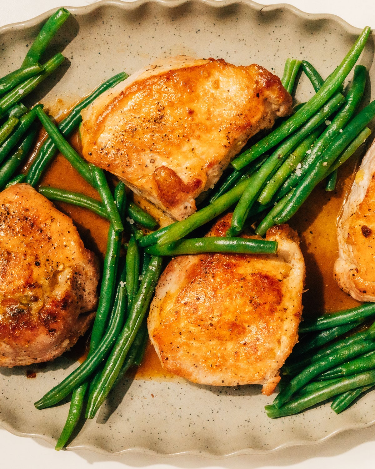 Stuffed pork chops with green beans on a platter.