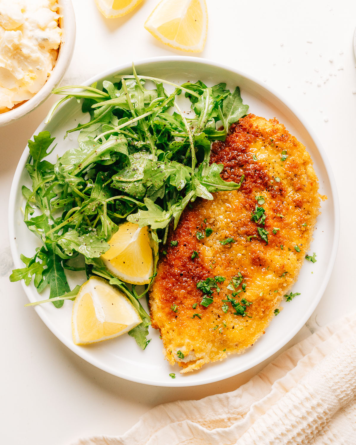 Golden brown and crispy finished chicken schnitzel with salad on the side.