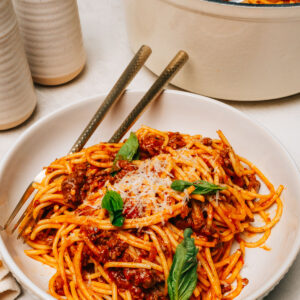 Spaghetti with ground beef served in a bowl topped with Parmesan cheese