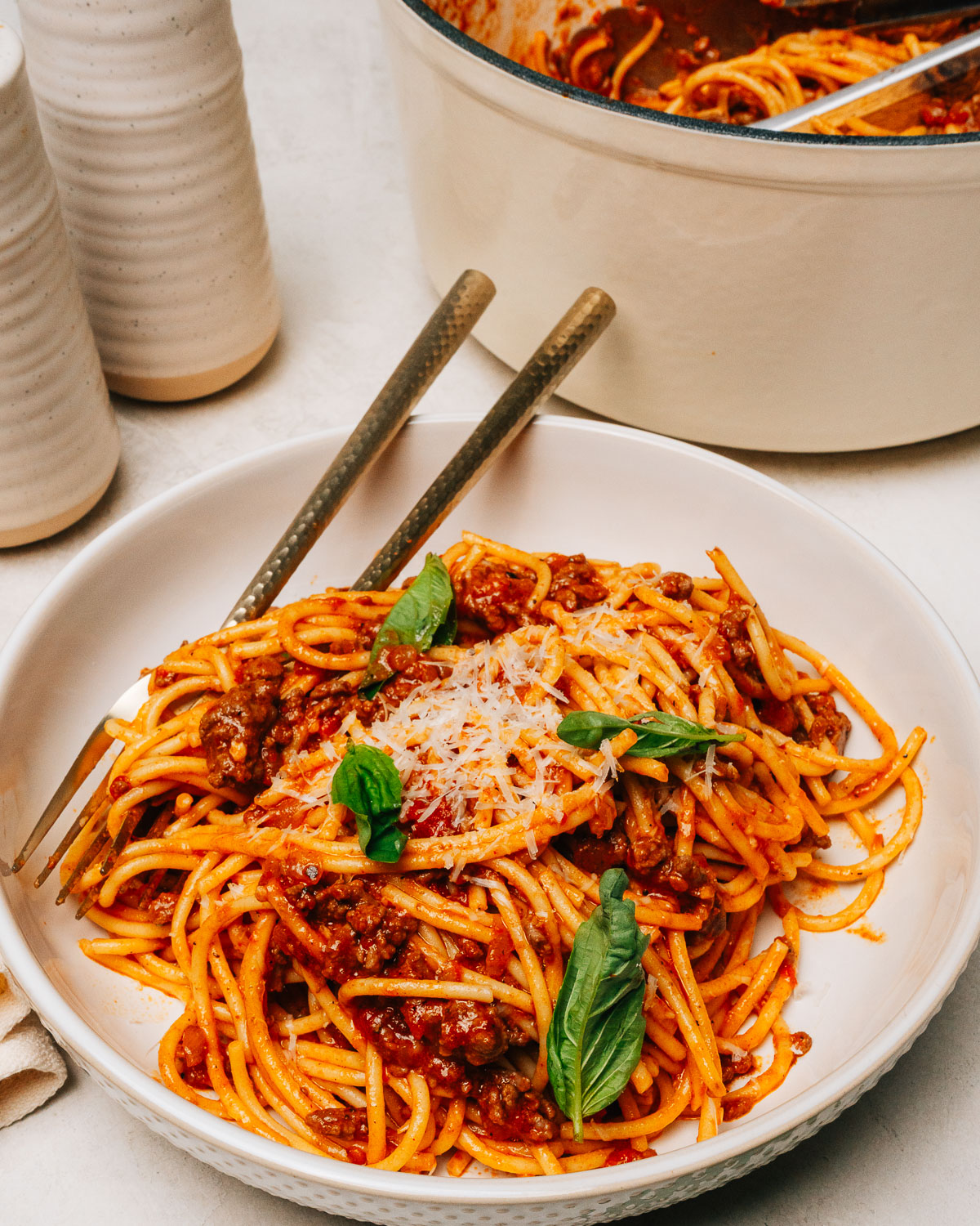 Spaghetti with ground beef served in a bowl topped with Parmesan cheese