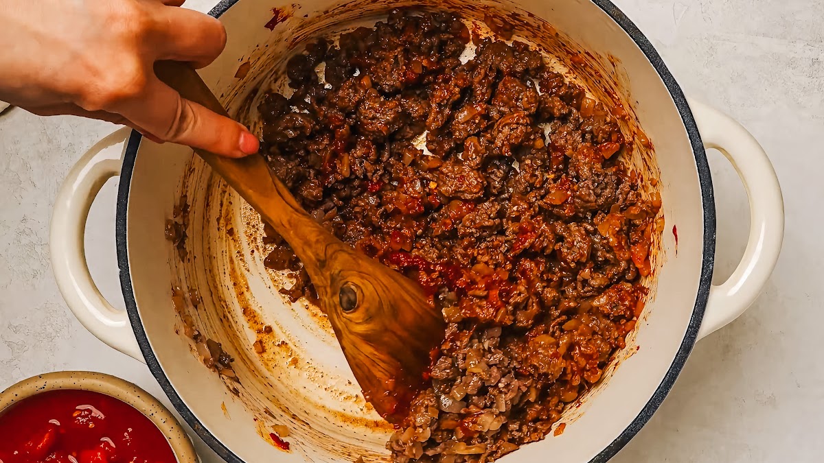 Toasting tomato paste in a pan until darkened for rich spaghetti sauce