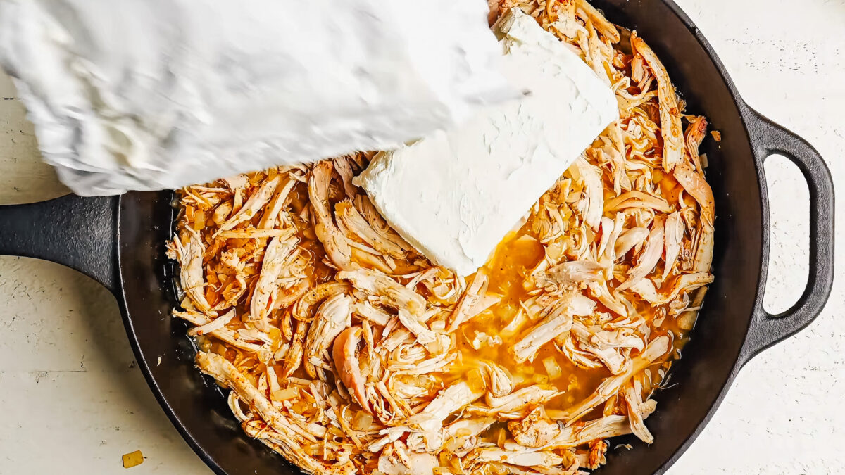 Adding cream cheese to chicken enchilada mixture