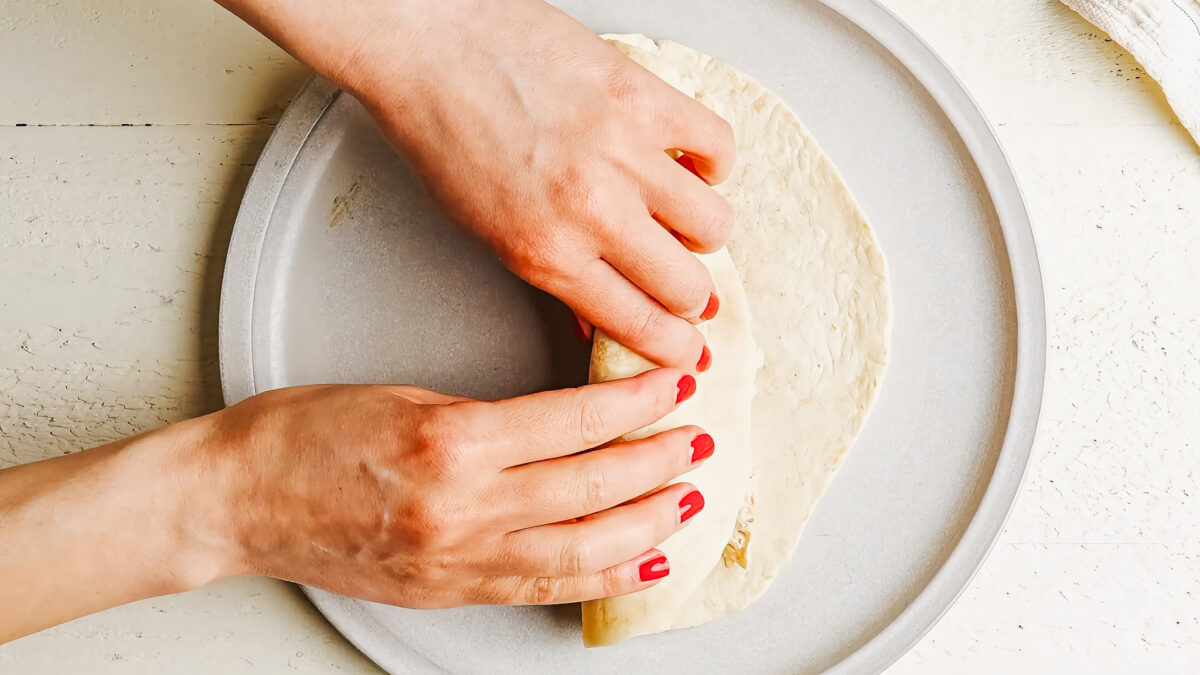 Rolling up cream cheese chicken enchilada.