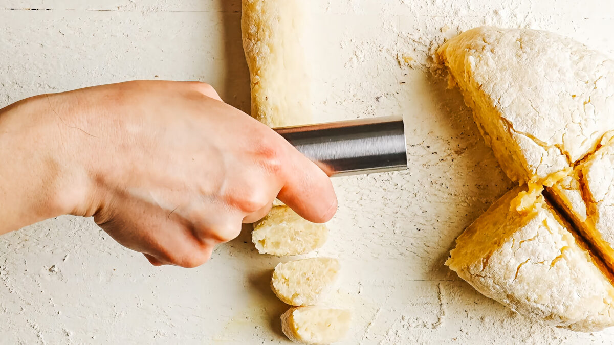 Rolling gnocchi dough into a rope and cutting it into bite-sized pieces