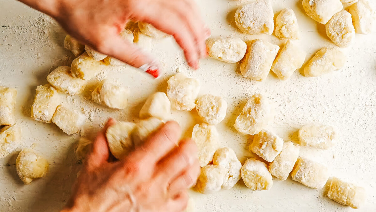 Shaping each gnocchi by rolling it along the tines of a fork to form ridges