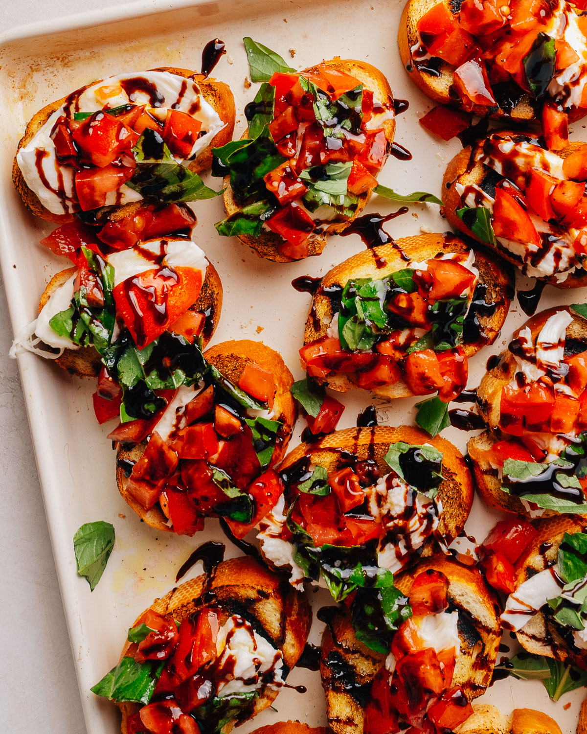 Overhead tray of bruschetta with mozzarella, tomato and basil.